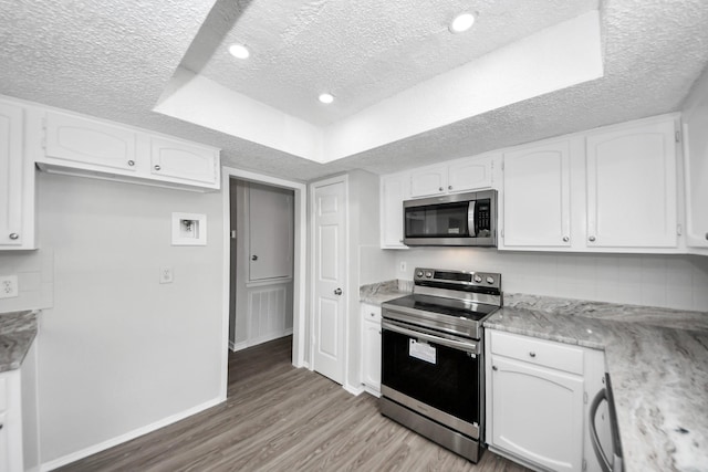 17715 Glenpatti Dr, Houston, TX 77084 - kitchen with stainless steel appliances, a textured ceiling, light wood finished floors, white cabinetry, and light stone countertops