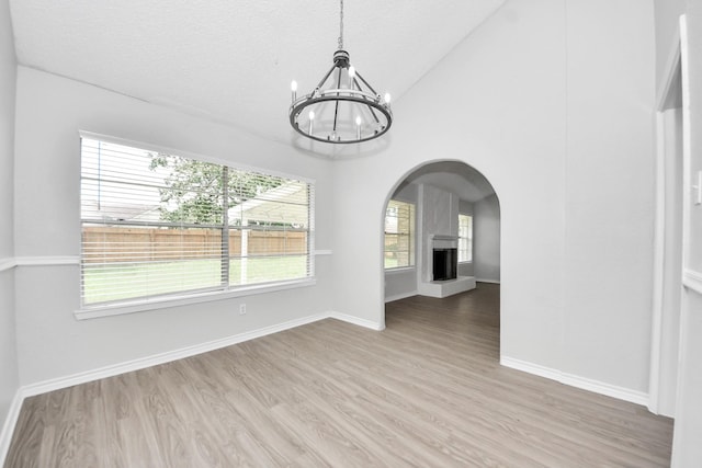 17715 Glenpatti Dr, Houston, TX 77084 - unfurnished dining area with a chandelier, arched walkways, wood finished floors, lofted ceiling, and a large fireplace