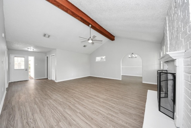 17715 Glenpatti Dr, Houston, TX 77084 - unfurnished living room featuring light wood-style floors, a textured ceiling, ceiling fan, a fireplace with raised hearth, and arched walkways