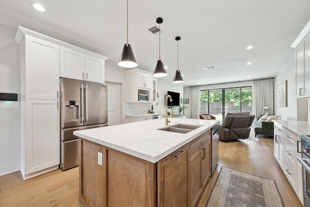 1810 Nauts Ct, Houston, TX 77008 - kitchen with stainless steel appliances, light wood-type flooring, white cabinets, open floor plan, and a kitchen island with sink