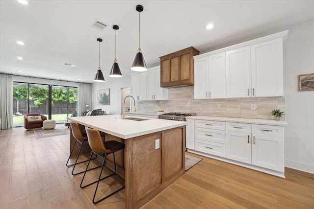 1810 Nauts Ct, Houston, TX 77008 - kitchen featuring light wood-style floors, backsplash, a kitchen island with sink, light countertops, and recessed lighting