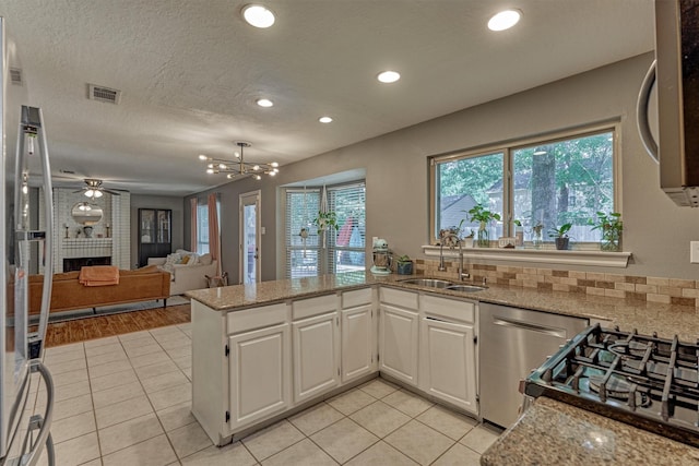 100 W Rainbow Ridge Cir, The Woodlands, TX 77381 - kitchen featuring stainless steel appliances, light stone countertops, light tile patterned flooring, white cabinetry, and tasteful backsplash