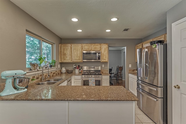100 W Rainbow Ridge Cir, The Woodlands, TX 77381 - kitchen featuring stainless steel appliances, stone counters, recessed lighting, a peninsula, and light brown cabinets