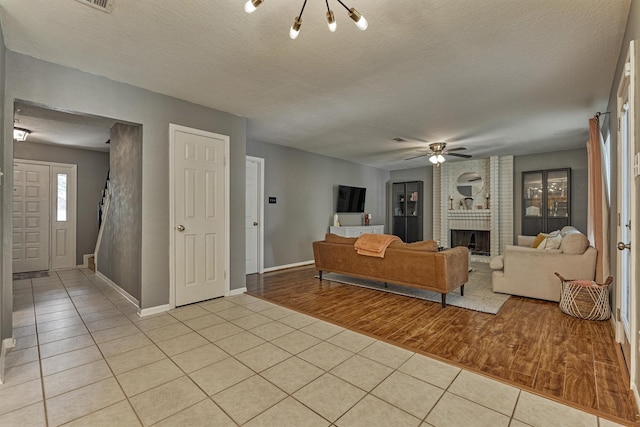100 W Rainbow Ridge Cir, The Woodlands, TX 77381 - living area with light tile patterned floors, a brick fireplace, ceiling fan, and a textured ceiling