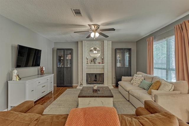 100 W Rainbow Ridge Cir, The Woodlands, TX 77381 - living area with ceiling fan, wood finished floors, a brick fireplace, and a textured ceiling
