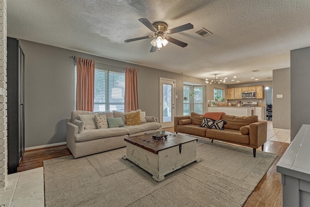 100 W Rainbow Ridge Cir, The Woodlands, TX 77381 - living area with a chandelier, light wood-style flooring, ceiling fan, and a textured ceiling