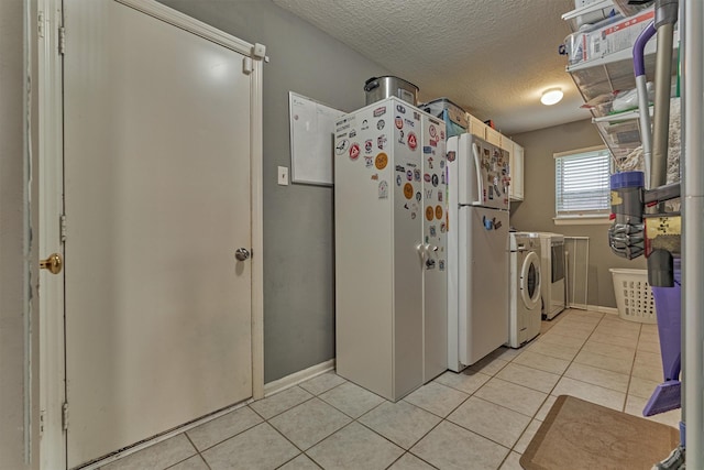 100 W Rainbow Ridge Cir, The Woodlands, TX 77381 - kitchen featuring washer and clothes dryer, freestanding refrigerator, light tile patterned floors, and a textured ceiling