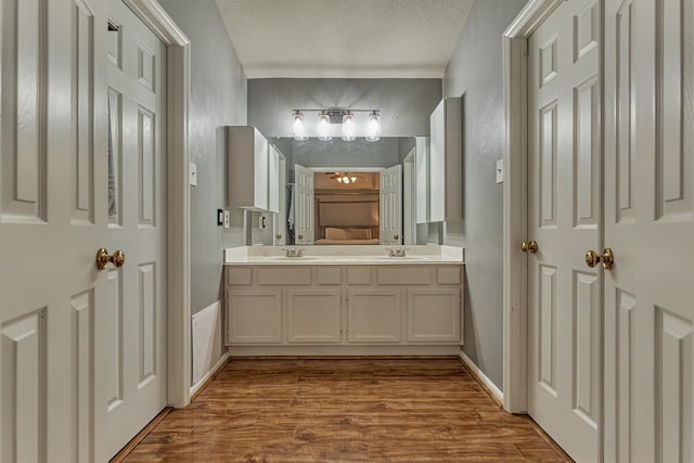 100 W Rainbow Ridge Cir, The Woodlands, TX 77381 - bathroom featuring wood finished floors, double vanity, a textured ceiling, and a textured wall