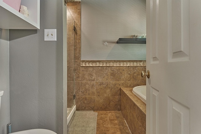 100 W Rainbow Ridge Cir, The Woodlands, TX 77381 - bathroom with a bath, a shower stall, and tile walls