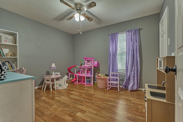 100 W Rainbow Ridge Cir, The Woodlands, TX 77381 - recreation room with a ceiling fan, light wood-style floors, and a textured ceiling