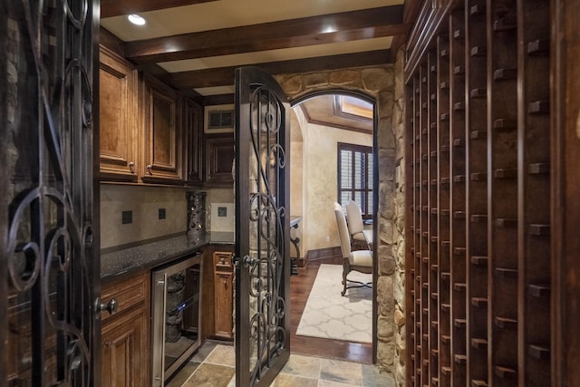 102 Lake Sterling Gate Dr, Spring, TX 77379 - wine area featuring wine cooler, arched walkways, beamed ceiling, and light stone finish floors