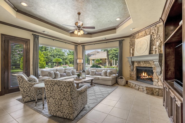 102 Lake Sterling Gate Dr, Spring, TX 77379 - living room with a tray ceiling, ornamental molding, light tile patterned flooring, a fireplace, and ceiling fan