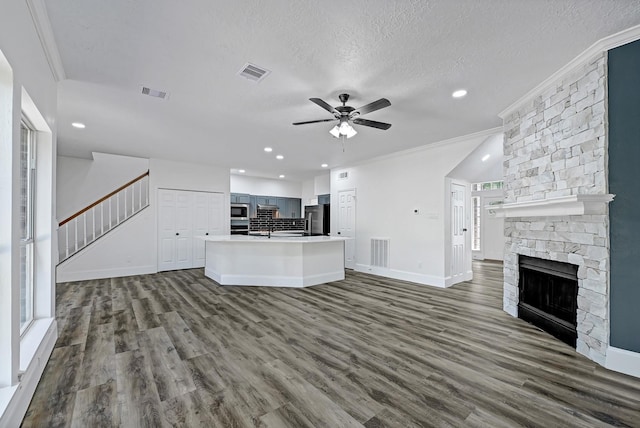 1826 Cheyenne River Cir, Sugar Land, TX 77478 - unfurnished living room featuring stairs, ceiling fan, a stone fireplace, dark wood finished floors, and crown molding