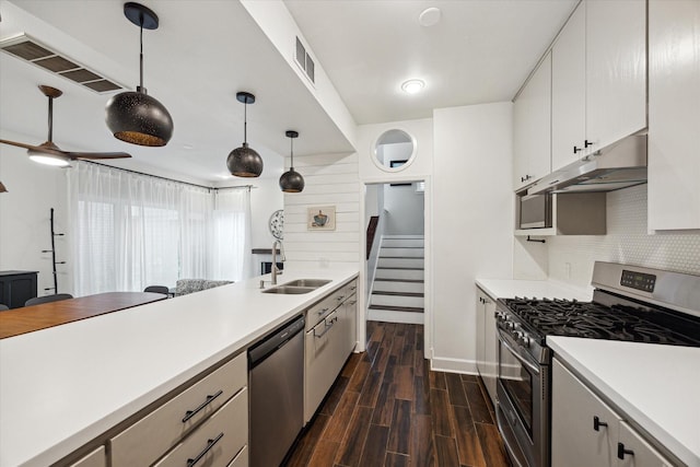 4914 Feagan St, Houston, TX 77007 - kitchen with appliances with stainless steel finishes, under cabinet range hood, dark wood finished floors, tasteful backsplash, and light countertops