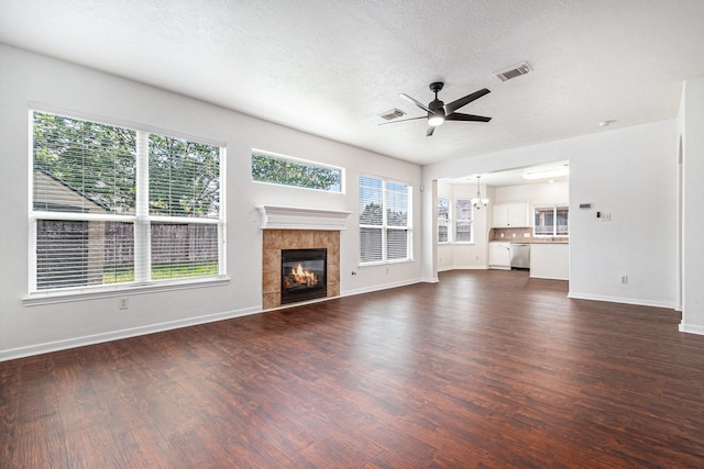 3242 Enchanted Hollow Ln, Spring, TX 77388 - unfurnished living room featuring ceiling fan, dark wood-style floors, a tiled fireplace, a textured ceiling, and a chandelier