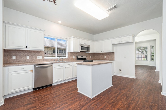 3242 Enchanted Hollow Ln, Spring, TX 77388 - kitchen with stainless steel appliances, arched walkways, white cabinets, backsplash, and dark wood finished floors
