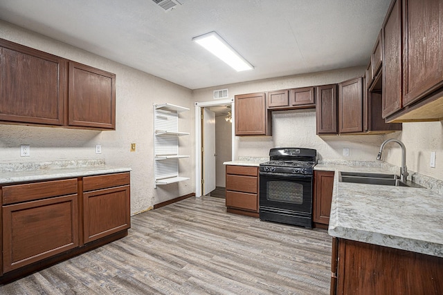 4028 N 1/2 Ave, Santa Fe, TX 77510 - kitchen featuring gas stove, light wood-type flooring, light countertops, and a textured wall