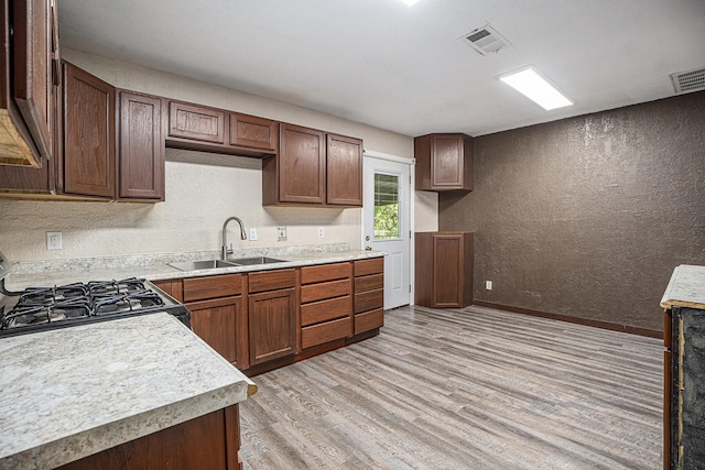 4028 N 1/2 Ave, Santa Fe, TX 77510 - kitchen featuring a textured wall, light wood-type flooring, range with gas cooktop, and light countertops