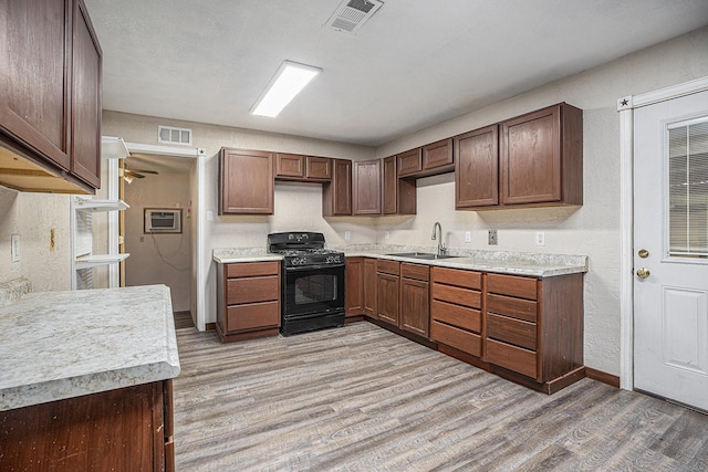 4028 N 1/2 Ave, Santa Fe, TX 77510 - kitchen featuring black gas stove, light wood-style floors, light countertops, an AC wall unit, and a textured wall