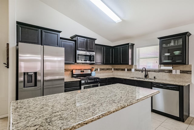 2010 Wembley Way, Rosenberg, TX 77471 - kitchen featuring stainless steel appliances, vaulted ceiling, dark cabinetry, light tile patterned flooring, and decorative backsplash