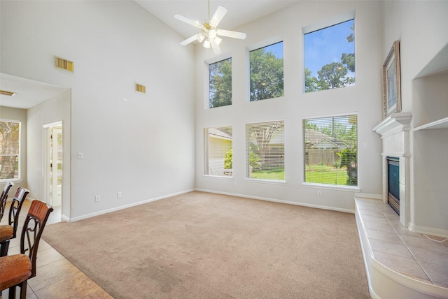 14311 Arlington Pl, Cypress, TX 77429 - unfurnished living room featuring high vaulted ceiling, light carpet, ceiling fan, light tile patterned floors, and a glass covered fireplace