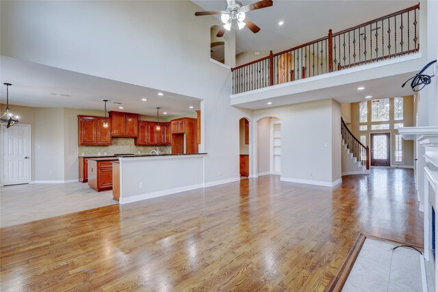 5507 Opal Cove Ct, Katy, TX 77494 - unfurnished living room featuring a high ceiling, arched walkways, a ceiling fan, light wood-style flooring, and stairs