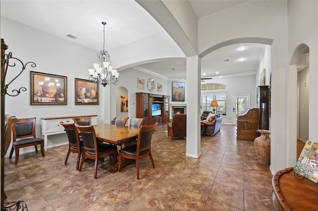 14733 Corvus Dr, Willis, TX 77318 - dining area featuring arched walkways, a warm lit fireplace, a chandelier, ornamental molding, and a ceiling fan