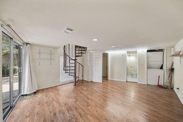 4723 Aftonshire Dr Unit 15, Houston, TX 77027 - unfurnished living room with stacked washer and clothes dryer, light wood-type flooring, and stairway