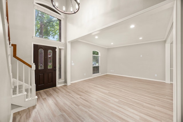 22 Windfern Pl, The Woodlands, TX 77382 - entrance foyer with a chandelier, stairway, ornamental molding, light wood finished floors, and a towering ceiling