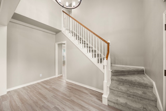 22 Windfern Pl, The Woodlands, TX 77382 - staircase featuring wood finished floors, a chandelier, and a towering ceiling