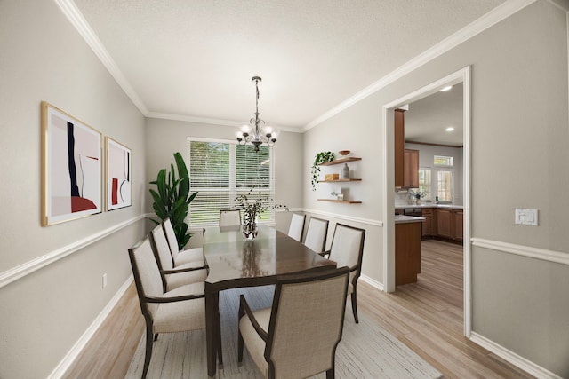 22 Windfern Pl, The Woodlands, TX 77382 - dining area with light wood finished floors, a chandelier, healthy amount of natural light, and crown molding