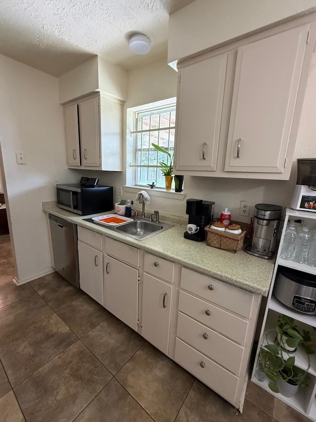 7431 Water Park Ln, Houston, TX 77086 - kitchen featuring stainless steel appliances, light countertops, a textured ceiling, dark tile patterned flooring, and white cabinets