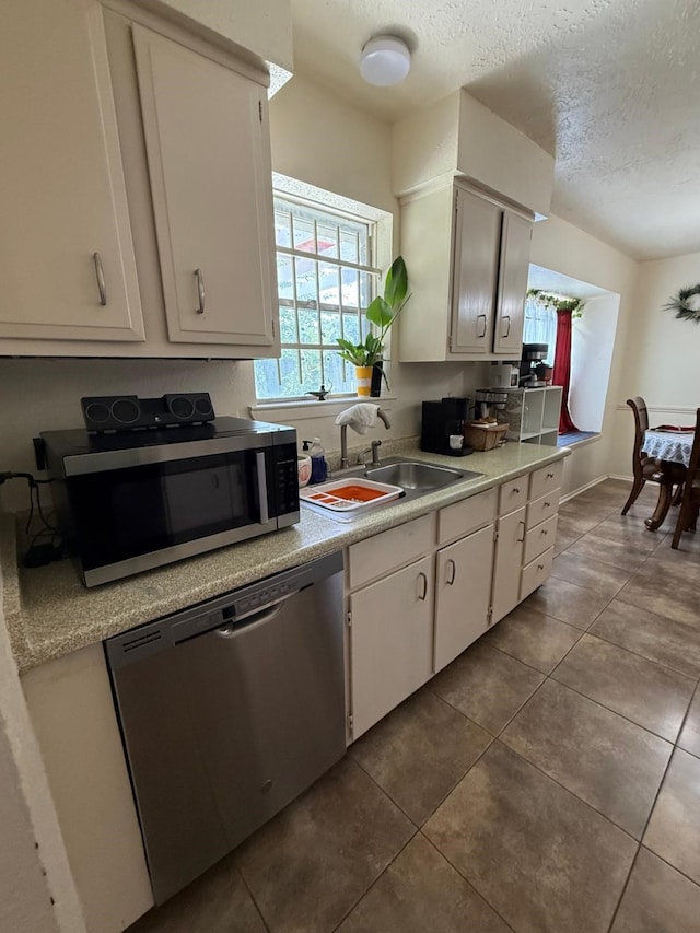 7431 Water Park Ln, Houston, TX 77086 - kitchen with stainless steel appliances, light countertops, a textured ceiling, dark tile patterned flooring, and white cabinets