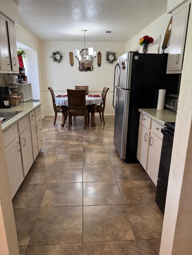 7431 Water Park Ln, Houston, TX 77086 - kitchen with range, a chandelier, a textured ceiling, light countertops, and decorative light fixtures