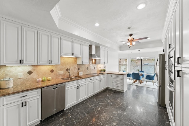 12013 Naughton St, Houston, TX 77024 - kitchen with appliances with stainless steel finishes, wall chimney range hood, a peninsula, a raised ceiling, and white cabinetry