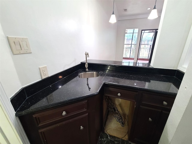12013 Naughton St, Houston, TX 77024 - kitchen with crown molding, dark stone counters, hanging light fixtures, and dark brown cabinets