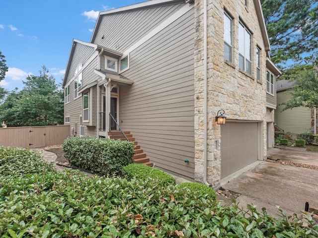211 Cheswood Forest Pl, Montgomery, TX 77316 - view of home's exterior featuring stone siding, an attached garage, and concrete driveway