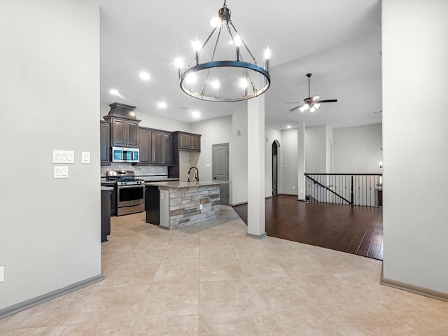 211 Cheswood Forest Pl, Montgomery, TX 77316 - kitchen featuring appliances with stainless steel finishes, open floor plan, a ceiling fan, arched walkways, and dark brown cabinets