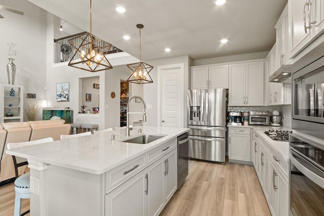 503 Highland Thicket Dr, Conroe, TX 77316 - kitchen featuring appliances with stainless steel finishes, a chandelier, a breakfast bar area, white cabinets, and light wood finished floors