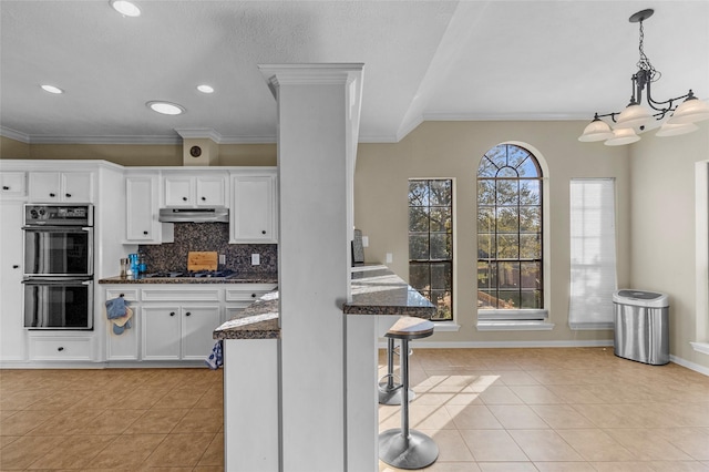 169 April Cv, Conroe, TX 77356 - kitchen with under cabinet range hood, light tile patterned floors, white cabinetry, recessed lighting, and crown molding