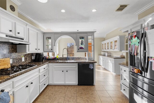 169 April Cv, Conroe, TX 77356 - kitchen with stainless steel appliances, crown molding, light tile patterned floors, arched walkways, and white cabinetry