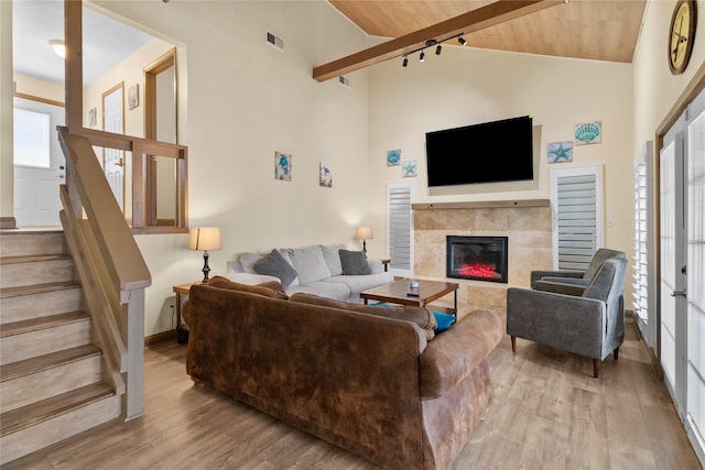 21216 Gulf Dr, Galveston, TX 77554 - living area with light wood-type flooring, high vaulted ceiling, a tile fireplace, stairway, and a wood ceiling with exposed beams