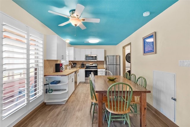 21216 Gulf Dr, Galveston, TX 77554 - dining area featuring stacked washing machine and dryer, light wood-style flooring, and a ceiling fan