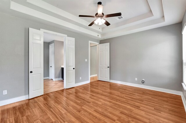 59 Beaconsfield Dr, Magnolia, TX 77355 - unfurnished bedroom with a raised ceiling, light wood-style flooring, and ceiling fan