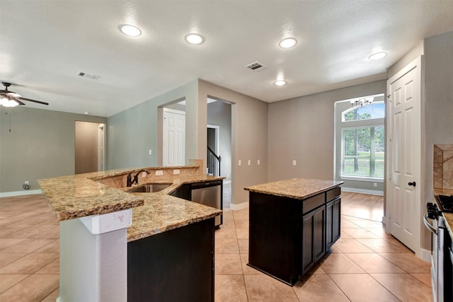 59 Beaconsfield Dr, Magnolia, TX 77355 - kitchen with a kitchen island with sink, appliances with stainless steel finishes, dark cabinets, a ceiling fan, and light tile patterned flooring