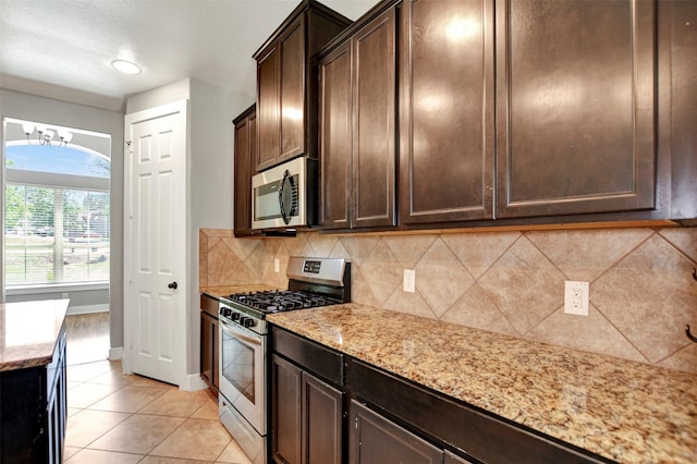 59 Beaconsfield Dr, Magnolia, TX 77355 - kitchen with appliances with stainless steel finishes, backsplash, a chandelier, dark brown cabinetry, and light stone counters