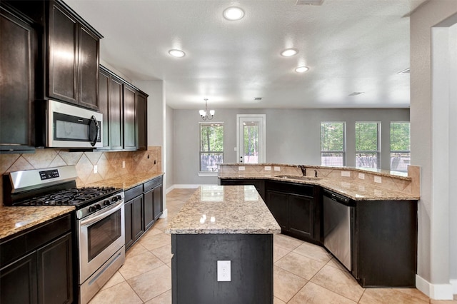 59 Beaconsfield Dr, Magnolia, TX 77355 - kitchen featuring appliances with stainless steel finishes, a center island, tasteful backsplash, light stone countertops, and recessed lighting