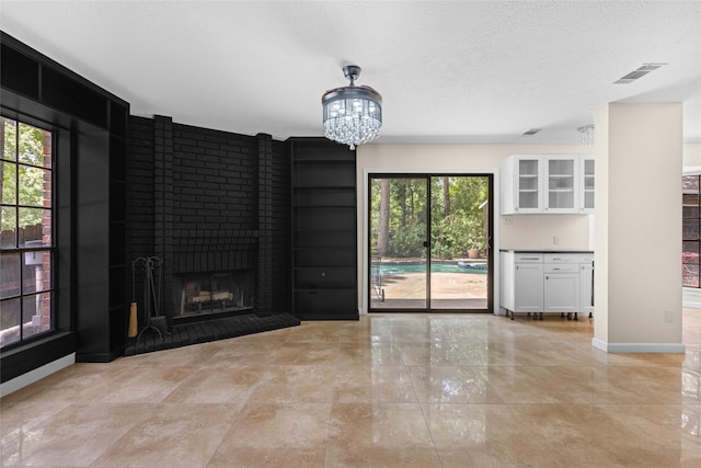 5 Cat Feet Ct, Spring, TX 77381 - unfurnished living room with a brick fireplace, a chandelier, and a textured ceiling