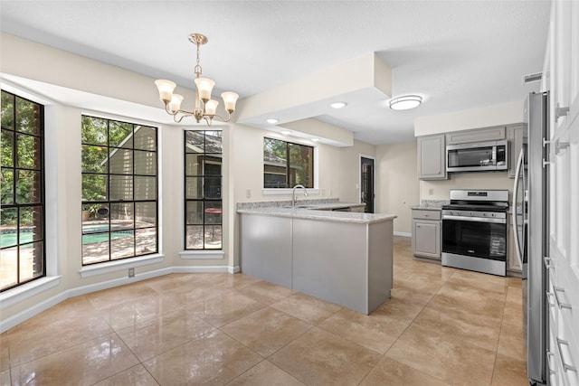 5 Cat Feet Ct, Spring, TX 77381 - kitchen with appliances with stainless steel finishes, gray cabinets, a peninsula, a chandelier, and healthy amount of natural light