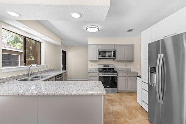 5 Cat Feet Ct, Spring, TX 77381 - kitchen with stainless steel appliances, gray cabinetry, a peninsula, and light stone counters